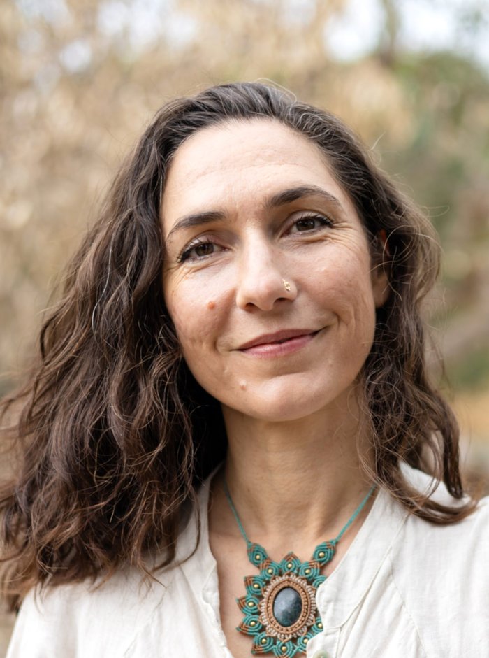Priya smiling softly outdoors, offering 1:1 trauma-sensitive embodiment coaching via Zoom or in-person